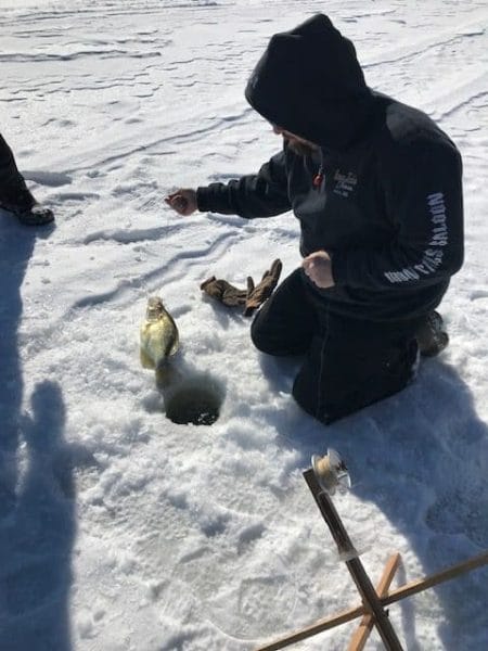 Pulling a crappie fish from the frozen lake.